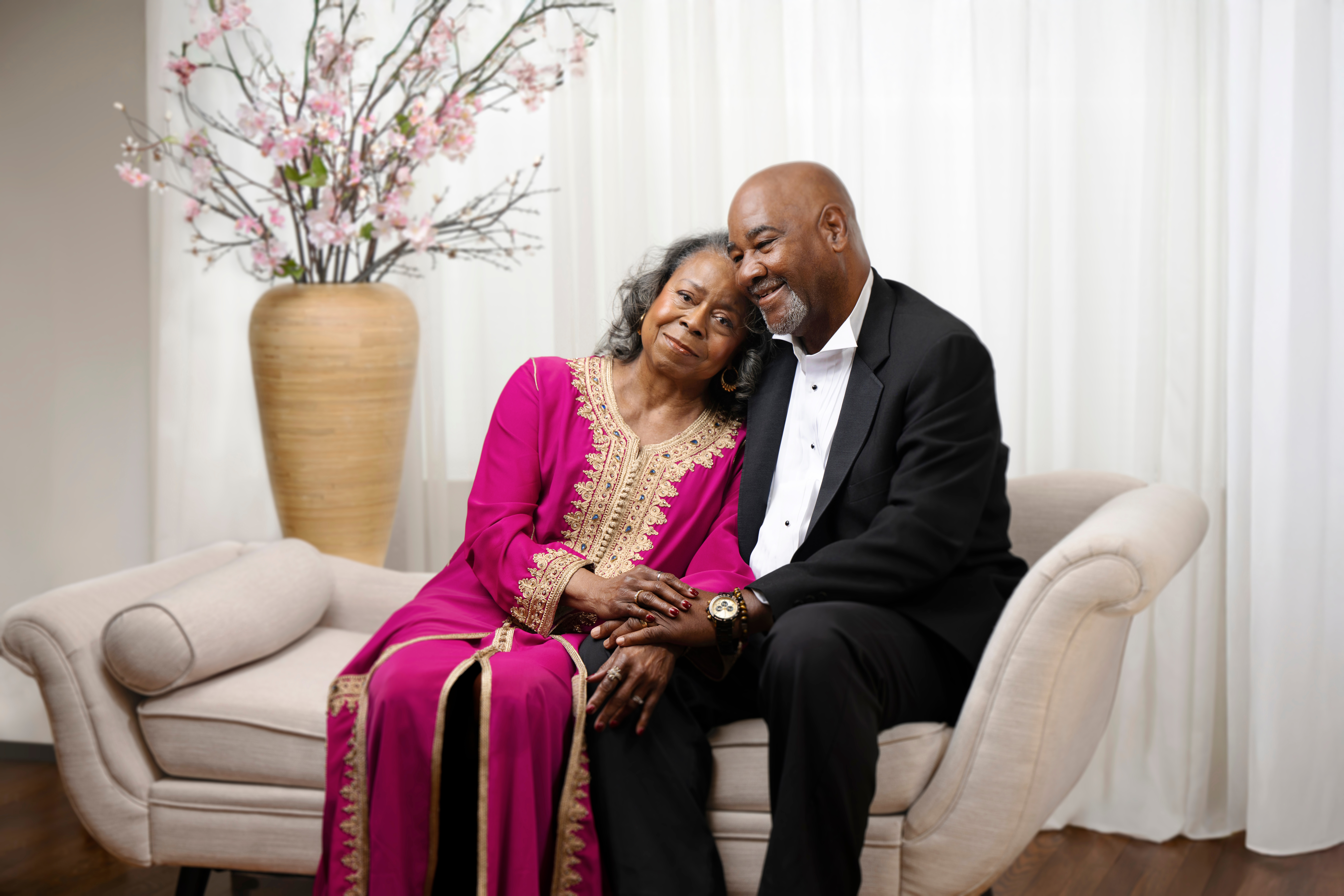 An older couple seated closely together, holding hands and smiling