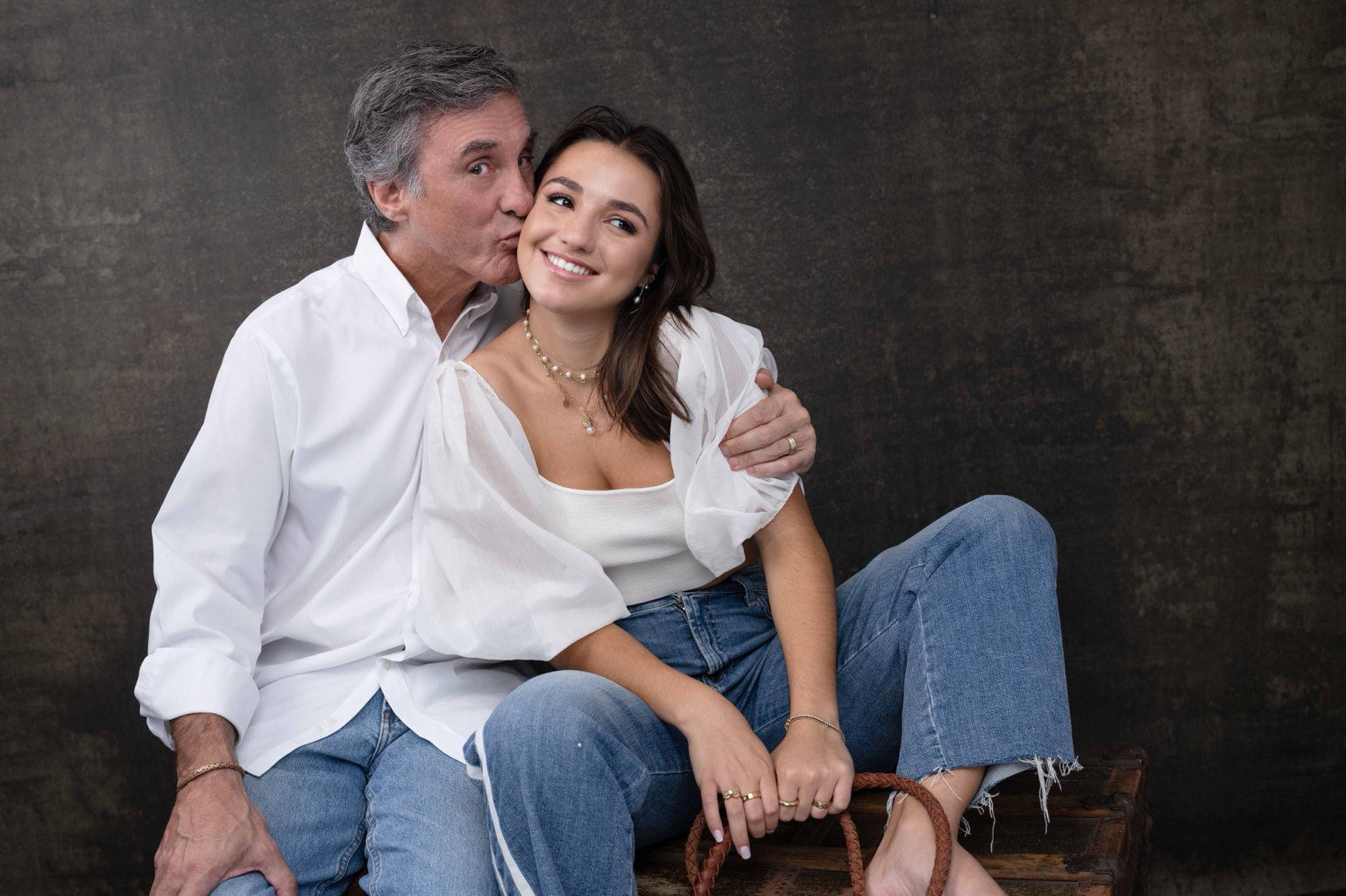A father kissing his smiling daughter on the cheek
